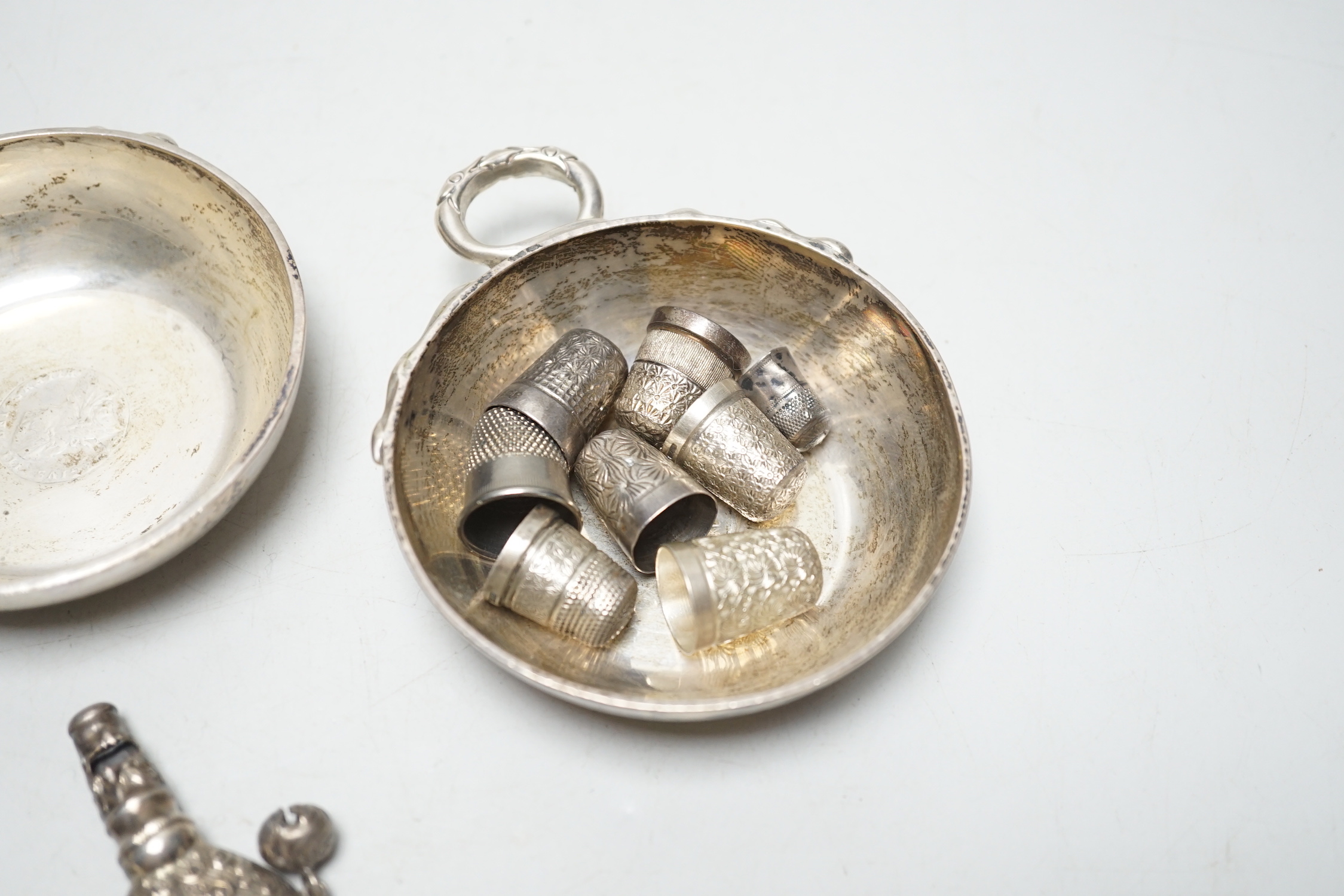 A pair of George V silver taste vin, D & J Welby Ltd, diameter 82mm, a late Victorian mother of pearl handled repousse silver child's rattle, one other larger similar silver rattle and eight thimbles including five silve